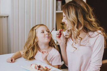mother and daughter in a cafe sitting at a table and feed each other ice cream.Good relationship of parents and child. Happy moments together.
