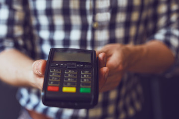 Male hands holding a payment terminal, toned
