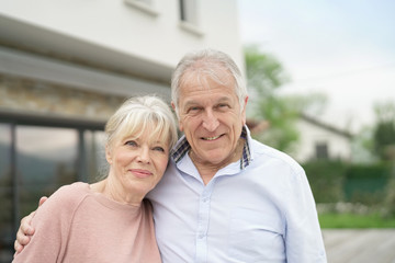 Senior couple embracing in front of new modern house