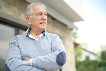 Senior man standing outside house