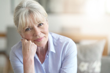 Portrait of blond senior woman standing in living room