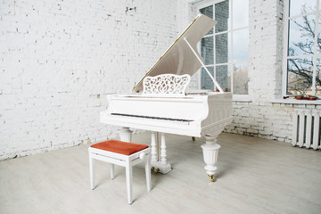 White piano in white room with brick wall