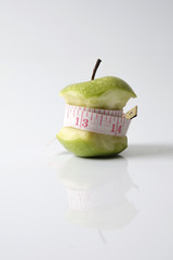 Close up of green apple with measuring tape isolated on white background.