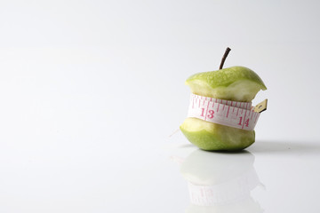 Close up of green apple with measuring tape isolated on white background.