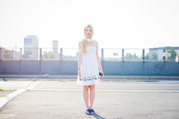Young beautiful woman in the city daylight posing looking camera holding smart phone - technology,...