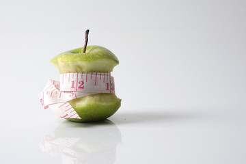 Close up of green apple with measuring tape isolated on white background.
