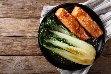 salmon in honey-soy glaze and fried bok choy close-up. Horizontal top view