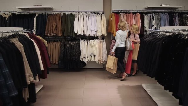Beautiful shopaholic women buying clothes in store