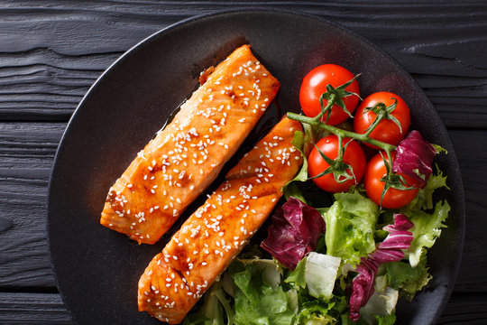 Glazed salmon fillet and fresh vegetable salad close-up on the table. Horizontal top view