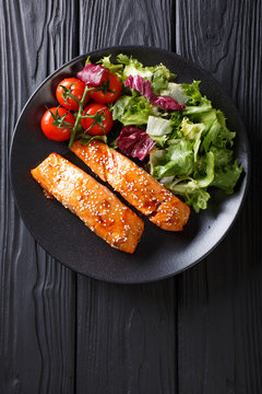 Glazed salmon fillet and fresh vegetable salad close-up on the table. Vertical top view