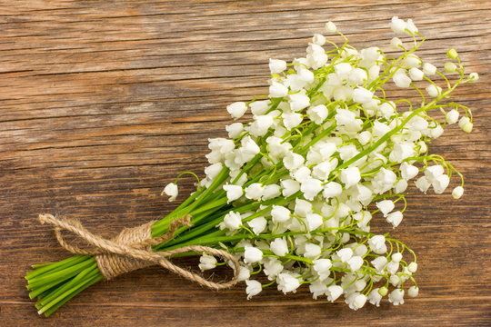 Vintage bouquet of wild flowers, the white scented lilies of the valley on an old wooden plank closeup