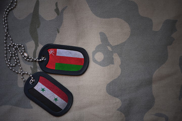 army blank, dog tag with flag of oman and syria on the khaki texture background. military concept