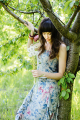 Beautiful girl with a romantic updo and professional makeup, the joy of white flowers in the garden. Dream-girl. Portrait of beautiful female model in the spring in the Park. dandelions in the hands