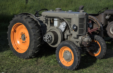  An old orange and green retro tractor in a field.