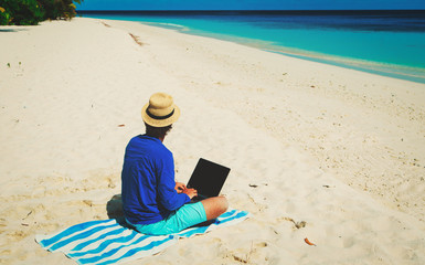 man with laptop on tropical beach