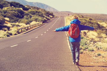 little boy travel on the road in mountains