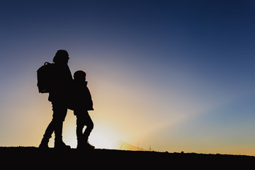 Fototapeta na wymiar Silhouettes of father and son hiking in sunset mountains