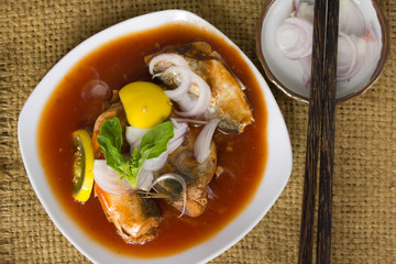 Canned fish with tomato sauce in white plate On old wood floor