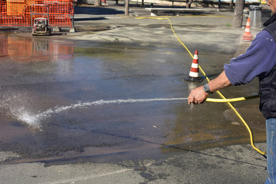 Un operaio pulisce la strada con l'acqua 
