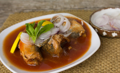 Canned fish with tomato sauce in white plate On old wood floor
