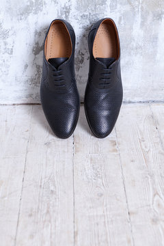 Black men's shoes against a wall in a retro interior in shades of gray.