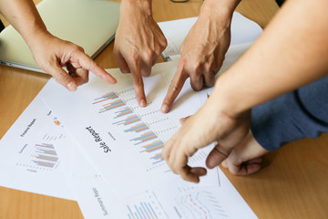 many fingers point at sale report charts paper on wooden desk