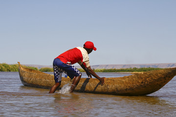 Young Malagasy rafter man rowing traditional canoe on river, Madagascar