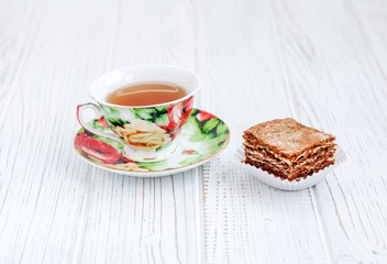 The piece of chocolate cake and a cup of tea on a white table. The concept of food and dessert.