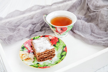Chocolate cake and a cup of hot tea on a tray. The concept of food and dessert.