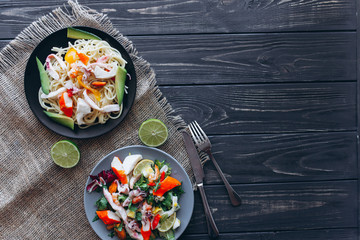 salad and pasta with seafood on wooden background