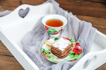 Delicious cake and a cup of hot tea on a tray. The concept of food and dessert.