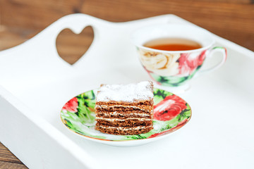Chocolate cake and a cup of hot tea on a white tray. The concept of food and dessert.