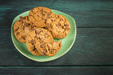 A teal plate of chocolate chips cookies with copyspace