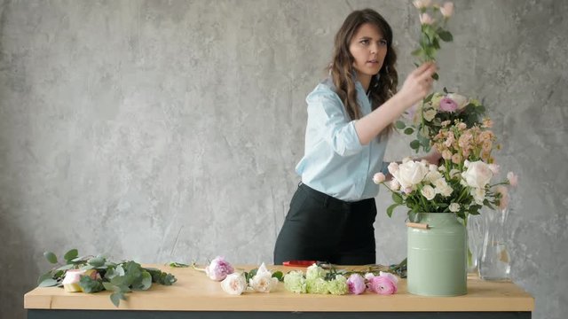 people, business, sale and floristry concept - happy smiling florist woman making bunch at flower shop, bouquet with peone and roses
