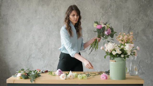 people, business, sale and floristry concept - happy smiling florist woman making bunch at flower shop, bouquet with peone and roses