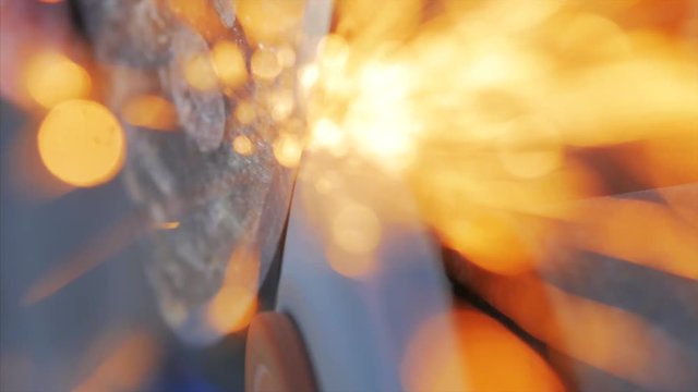 A man sharpens an ax on a machine with sparks.