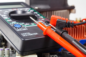 Digital multimeter with colored probes on the computer motherboard closeup