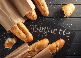 French baguettes with sesame seed on black wooden background