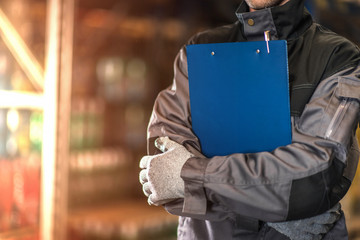 Warehouse worker with blue clipboard closeup photo.