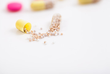 Yellow capsules on white background, one split open, copy space.