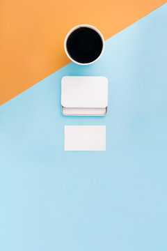 Stationary mock up on blue and orange background. Coffee, white card holder and business card