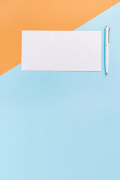 Stationary mock up on blue and orange background. White envelope and pen