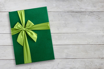 Green gift box over wood background with copy space, top view