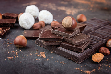 Dark chocolate pieces with nuts and cocoa  on dark  background,  selective focus