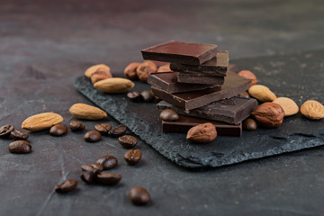 Dark chocolate pieces with nuts and cocoa  on dark  background.