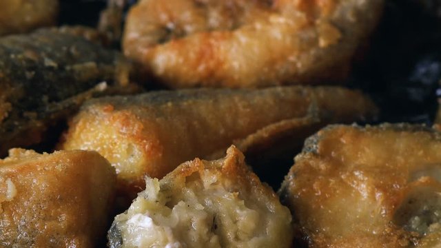 Frying hake fish outdoors on picnic, close up of frying pan with oil and fish slices