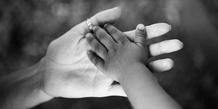 Child's hand in the hand of an adult. Black and white photo about the trust and joy of parenting and childhood