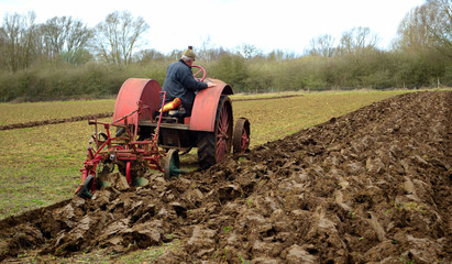  Vintage red International 1930's  tractor ploughing field. 