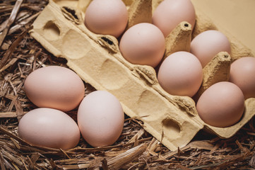 Eggs in yellow box on rustic hay.