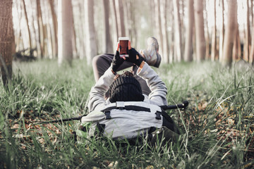 Man backpacker lying on the mountain using a mobile
